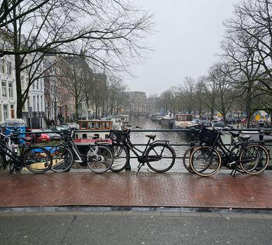 Weer vandaag Amsterdam boven Centraal Station met wolken, zon en reizigers op het Stationsplein