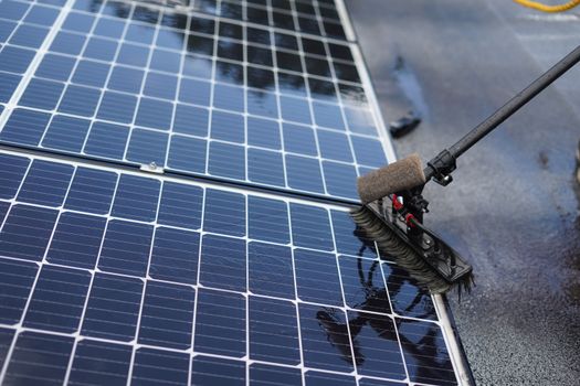 Huiseigenaar maakt zonnepanelen voorzichtig schoon met zachte telescoopborstel op een zonnige dag