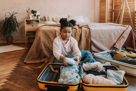 Open koffer met zomer- en winterkleding, zonnebrand, snowboots en reisdocumenten netjes uitgestald