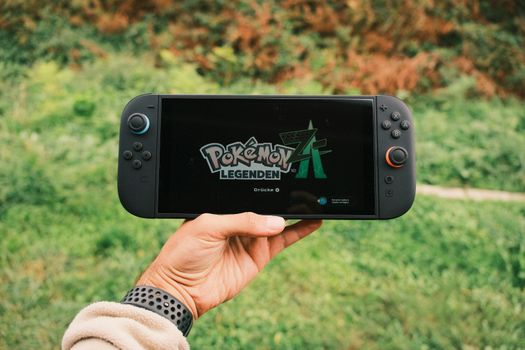 Nintendo Switch 2 console met handheld scherm en controllers naast een tv in moderne woonkamer