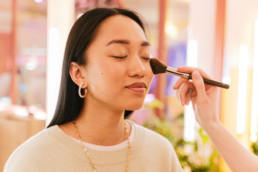 Vrouw brengt Rare Beauty blush aan voor spiegel met zachte natuurlijke glow