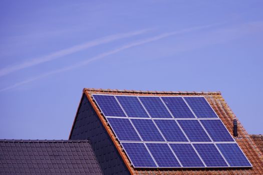 Huiseigenaar bekijkt thuisbatterij naast omvormer en zonnepanelen op het dak in 2026